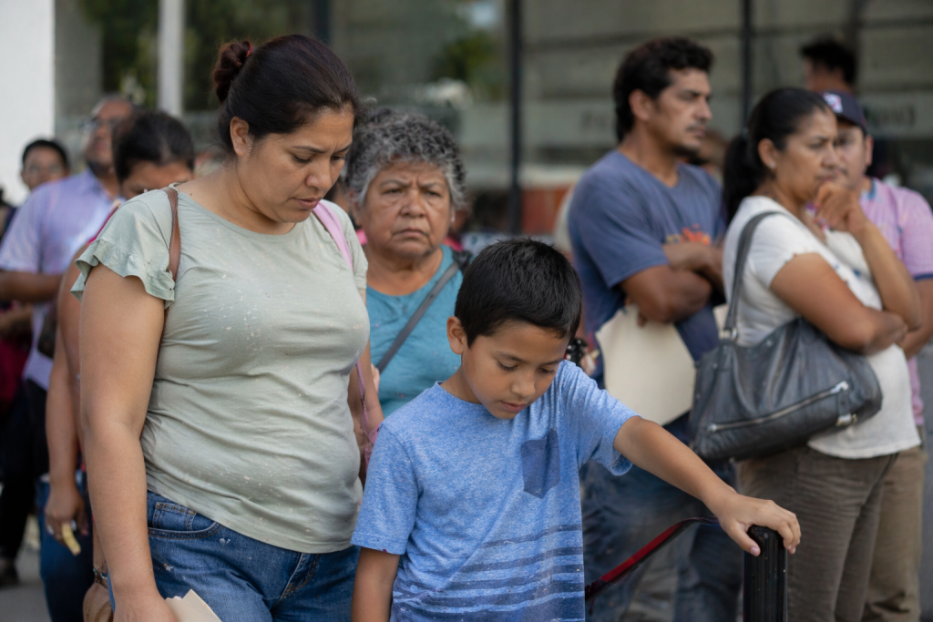 Personas hacen fila en m&oacute;dulo de Bienestar en M&eacute;xico madre con hijo con autismo esperando tr&aacute;mite con incertidumbre
