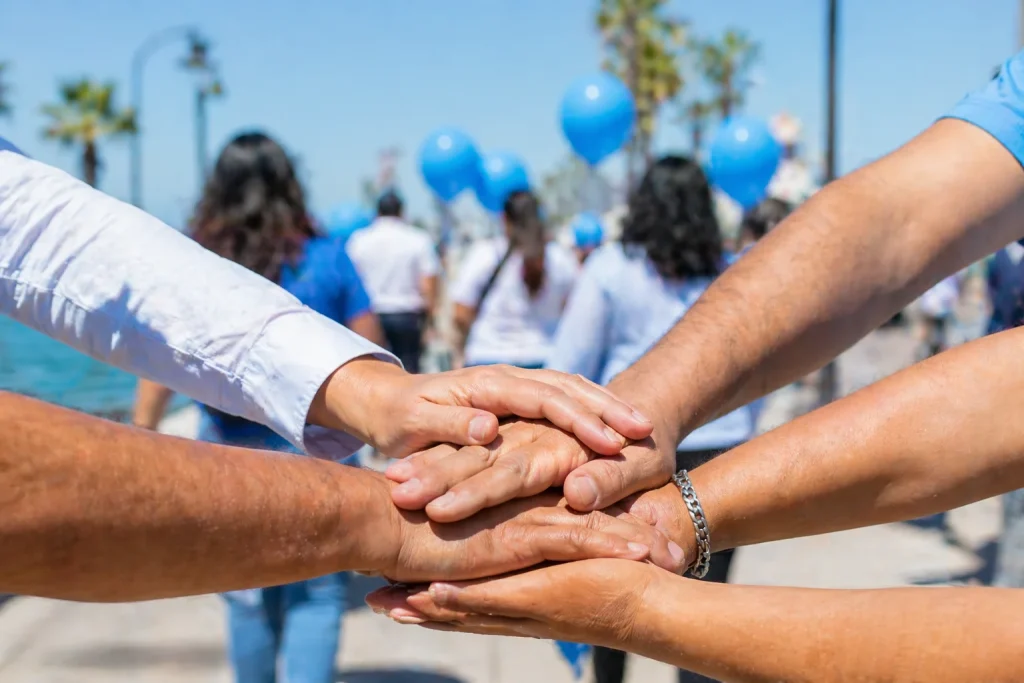 Manos de personas adultas unidas en círculo durante evento de inclusión por el autismo en La Paz Baja California Sur.